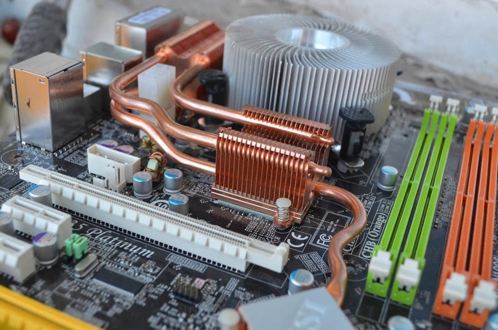 Inside a desktop computer: motherboard, CPU cooler with copper heat pipes, and memory modules